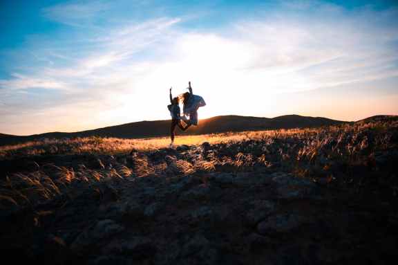 two person jumping on brown soil